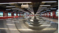 Blick in einen nahezu menschenleeren Gang der U-Bahn von Hongkong. Rechts und links beleuchtete Werbekästen, an der Decke zahlreiche Neonröhren, die sich auf dem Boden spiegeln