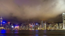 Blick über Wasser auf die nächtlich beleuchtete Skyline von Hongkong