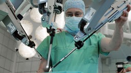 Ein Urologie-Chirurg stellt die Arme des ferngesteuerten Operationsassistenten "da Vinci" ein.