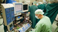 Ein Arzt überwacht bei einer Herz-Operation eine Herz-Lungen-Maschine.