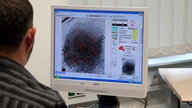 Ein Mitarbeiter des Landeskriminalamtes beim Fingerabdruckvergleich im Laborraum.