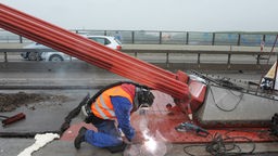 Auf der Rheinbrücke verschweißt ein Bauarbeiter Stahlplatten