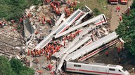 Eine Luftbildaufnahme zeigt die vielen Helfer, die Wrackteile des Zuges und die eingestürzte Brücke 