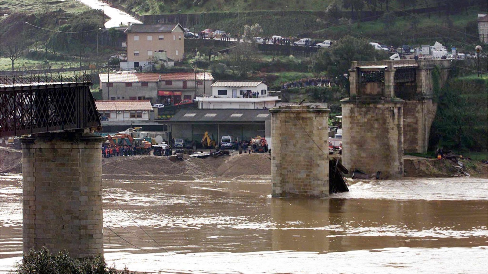 Die Brückenpfeiler ragen aus dem Fluss. Im Hintergrund stehen Massen an Schaulustigen. 