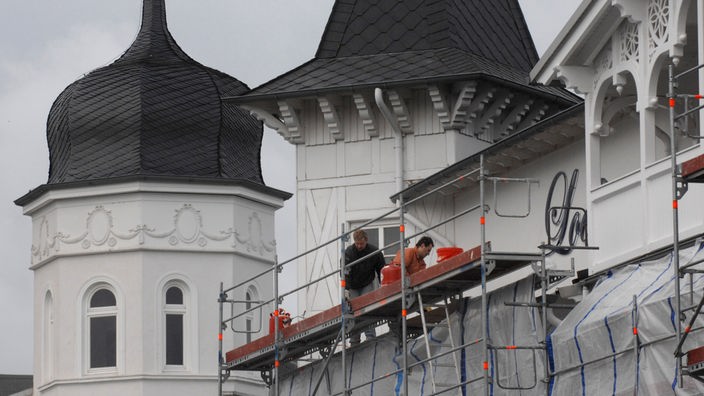 Bauarbeiter sanieren die Fassade und das Dach einer historischen Villa