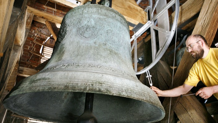 Der Orgel- und Glockensachverständige der Evangelischen Kirche der Kirchenprovinz Sachsen, Christoph Schulz, prüft mit verstellbaren Präzisionsstimmgabeln die Tonlage einer großen Glocke in der Marktkirche