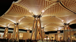 Nur schemenhaft zu erkennen sind Expo-Besucher, die auf der Weltausstellung in Hannover unter dem größten freitragenden Holzdach der Welt entlang laufen
