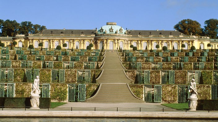 Zwischen den Gärten erstreckt sich eine lange Treppe bis zum goldgelben Schloss Sanssouci.