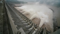 Staumauer am Drei-Schluchten-Staudamm in China. Riesige Wasserfontänen schießen aus der Mauer.