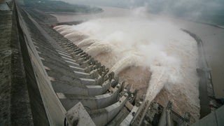Staumauer am Drei-Schluchten-Staudamm in China. Riesige Wasserfontänen schießen aus der Mauer.