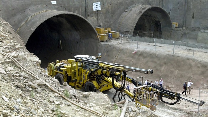 Baustelle: Neben zwei noch nicht fertig gestellten Tunnelröhren steht ein schweres Baufahrzeug.