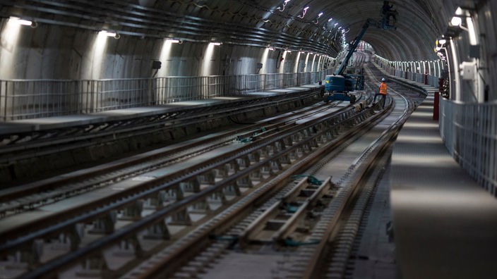 In einem kurvig verlaufenden U-Bahntunnel führen Arbeiter Wartungsarbeiten durch