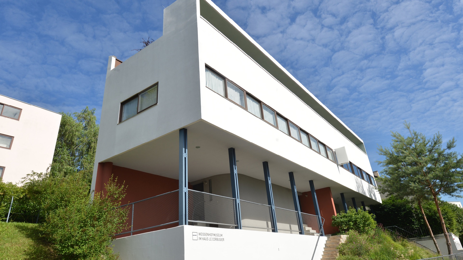 Ein Wohnblock, der nicht auf Grundmauern lastet, sondern von Stützen getragen wird. Wie ein weißer Quader ruhen die Wohneinheiten darauf. Die Fensterreihe erscheint als durchgehender Streifen. | Bildquelle: dpa / Franziska Kraufmann Ein Wohnblock, der nicht auf Grundmauern lastet, sondern von Stützen getragen wird. Wie ein weißer Quader ruhen die Wohneinheiten darauf. Die Fensterreihe erscheint als durchgehender Streifen.