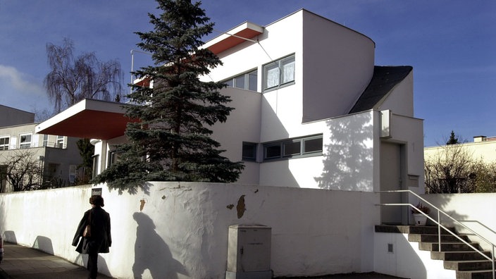 Weißes Wohngebäude der Weißenhof-Siedlung mit großzügiger Terrasse, rund geschwungener Mauer und flachem Dach. | Bildquelle: dpa/Norbert Försterling Weißes Wohngebäude der Weißenhof-Siedlung mit großzügiger Terrasse, rund geschwungener Mauer und flachem Dach.