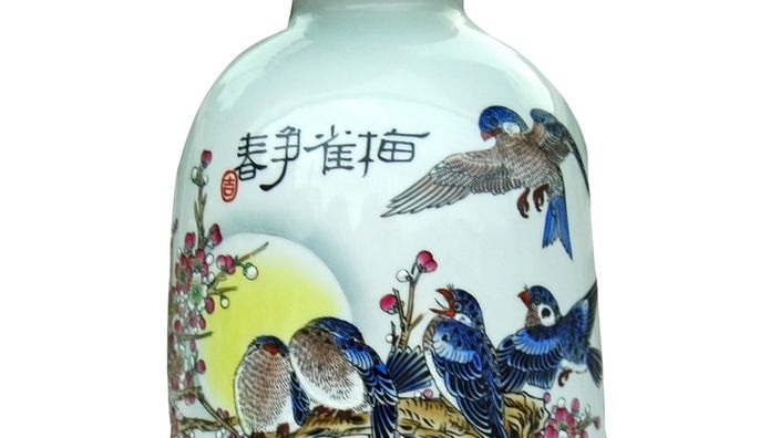 Eine weiße bauchige Porzellanvase, auf der blaue Vögel zu sehen sind, die auf einem Ast sitzen
