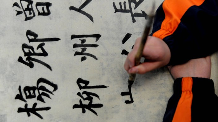 Schüler schreibt chinesische Schriftzeichen