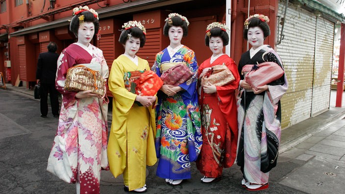 Eine Gruppe Geishas in farbigen Gewändern, den sogenannten Kimonos, aud den Straßen Tokyos