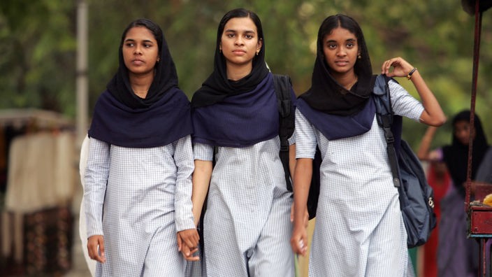 Drei junge Inderinnen in Schuluniform halten sich an der Hand.