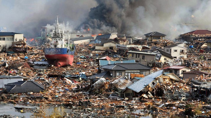 Das Bild vom 12. März 2011 zeigt brennende Häuser, Trümmer und Schiffe, die durch den Tsunami an Land gespült wurden