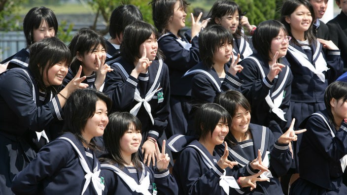 Japanische Schülerinnen in Schuluniform posieren für ein Foto.