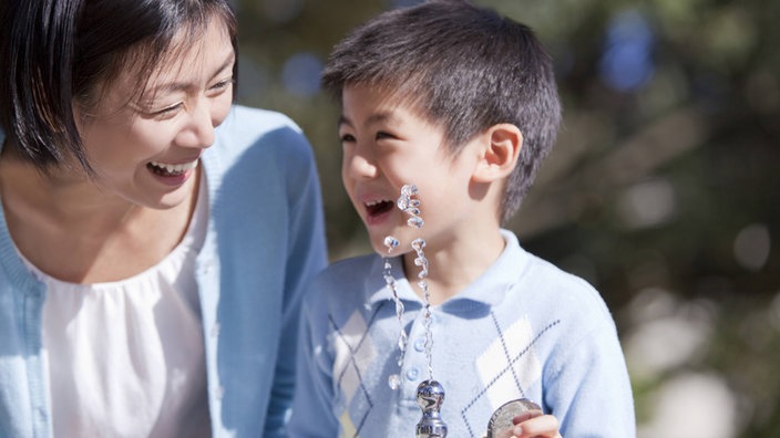 Eine japanische Mutter mit ihrem Sohn an einem Springbrunnen | Bildquelle: imago Eine japanische Mutter mit ihrem Sohn an einem Springbrunnen