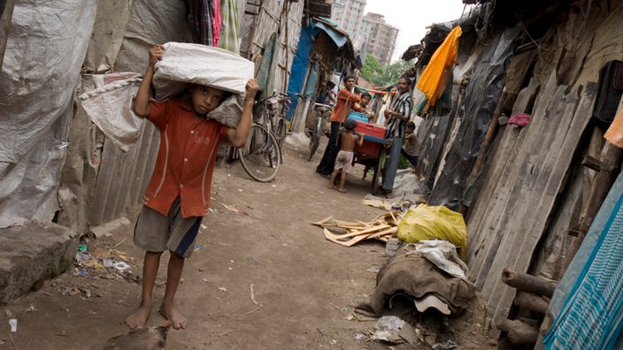 Kleiner Junge trägt einen Sack mit Müll durch die Slums von Kalkutta