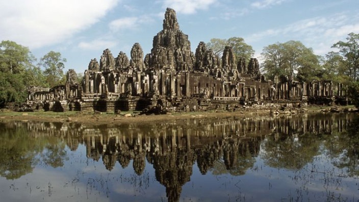 Das Bild zeigt einen großen Tempel mit vielen kleinen terrassenförmigen und unterschiedlich hohen Türmen. Er spiegelt sich in einem Wassergraben im Vordergrund. | Bildquelle: akg Das Bild zeigt einen großen Tempel mit vielen kleinen terrassenförmigen und unterschiedlich hohen Türmen. Er spiegelt sich in einem Wassergraben im Vordergrund.