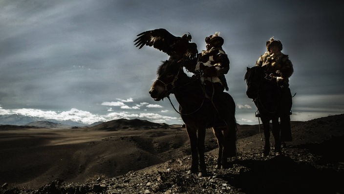 Altaierscher Vater und Sohn auf ihren Pferden mit einem Adler auf dem Arm.