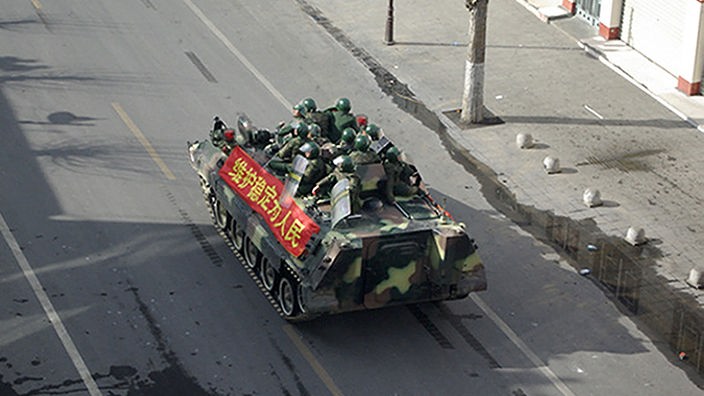 Blick von oben auf einen Panzer, der über eine Straße in Lhasa fährt.