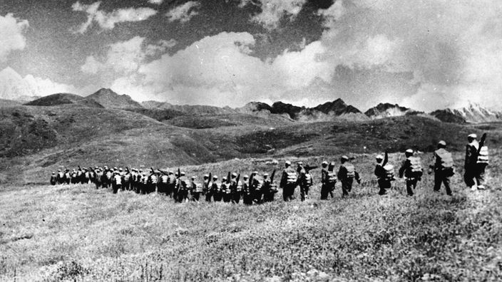 Schwarzweiß-Bild: Chinesische Soldaten marchieren im tibetischen Hochland.