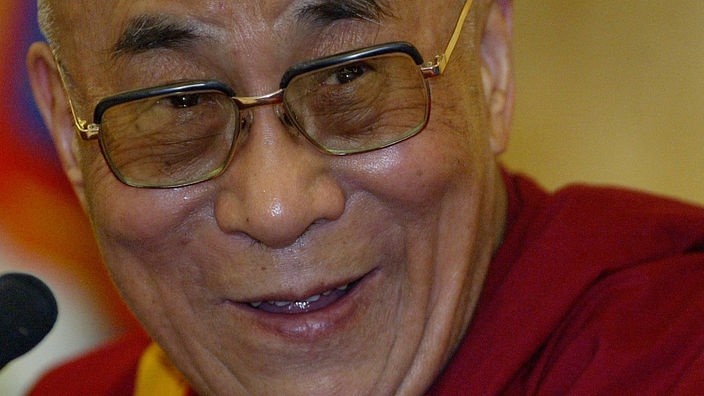 Der DalaiLama lacht in die Kamera.