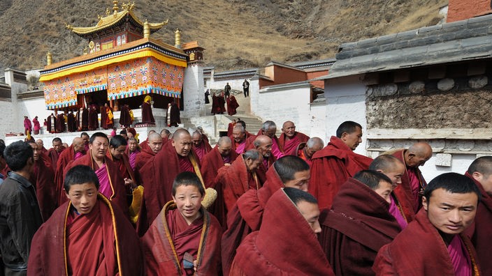 Viele Mönche verschiedenen Alters in roten Gewändern schauen in die Kamera.