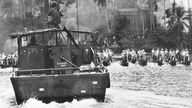 Schwarzweiß-Foto: Szene aus dem Film 'Apocalypse Now', in der ein amerikanisches Schiff auf einem Fluss von Flößen umzingelt wird.