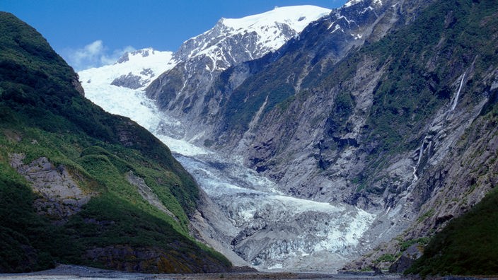 Das Bild zeigt einen Gletscher. Im Hintergrund ist ein schneebedeckter Gipfel zu sehen.