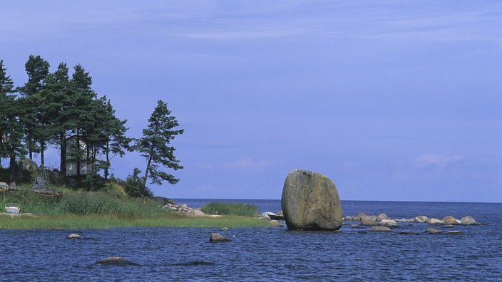 Ein großer Felsbrocken liegt an der Küste im Wasser, um ihn herum viele kleinere.