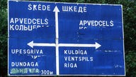 Straßenschild mit lettischer und teils überklebter russischer Schrift.
