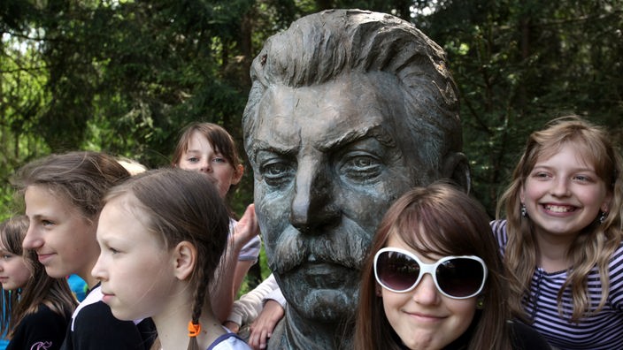 Stalin-Skulptur, umrahmt von mehreren jungen Mädchen.