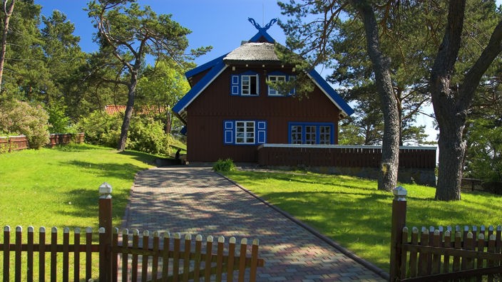 Braunes Holzhaus mit blauen Verzierungen.