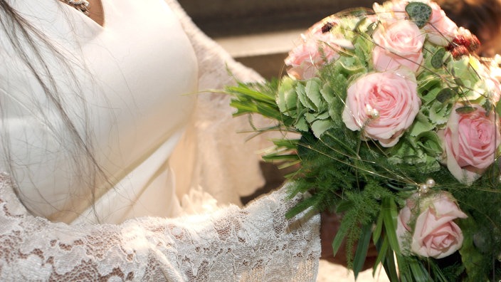 Braut in weißem Kleid hält einen Brautstrauß aus rosafarbenen Rosen in der Hand | Bildquelle: dpa Braut in weißem Kleid hält einen Brautstrauß aus rosafarbenen Rosen in der Hand