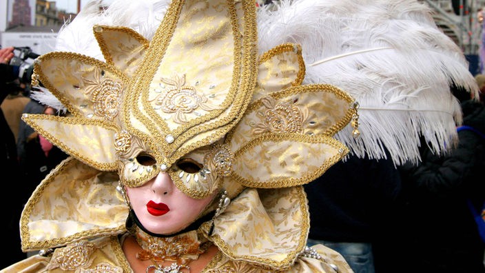 Goldfarbene venezianische Maske mit großem Federkopfputz.