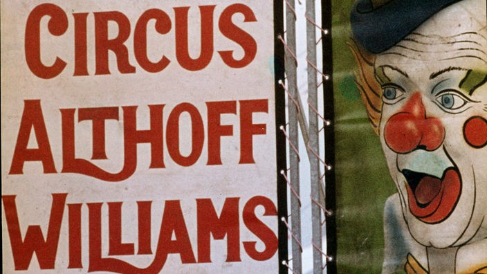 Plakat eines Zirkus: Auf der linken Hälfte steht 'Circus Althoff Williams' auf der erchten Seite ist ein gemaltes Clownsgesicht zu sehen.