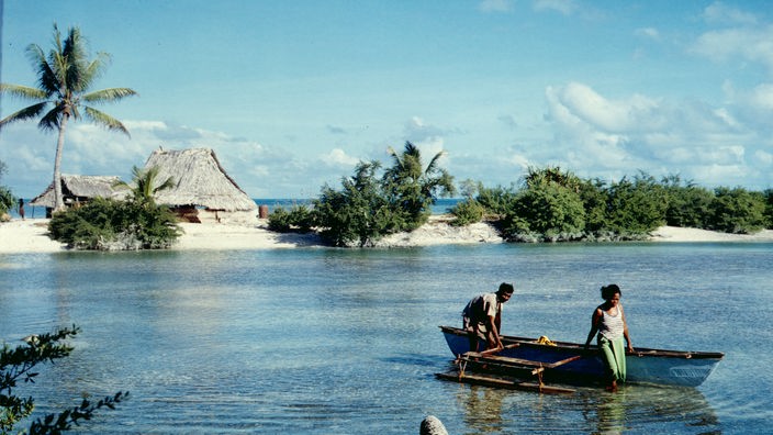 Ein Paar mit einem kleinen Fischerboot auf einer Südseeinsel