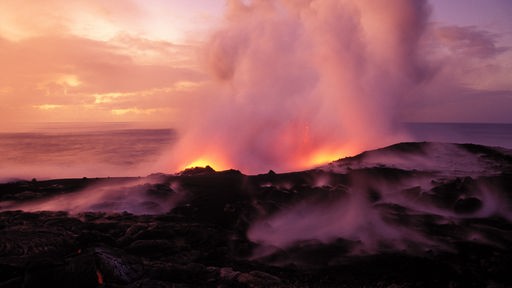 Im Vordergrund dampfende Lava, im Hintergrund glühendes Gestein in roter Abenddämmerung.