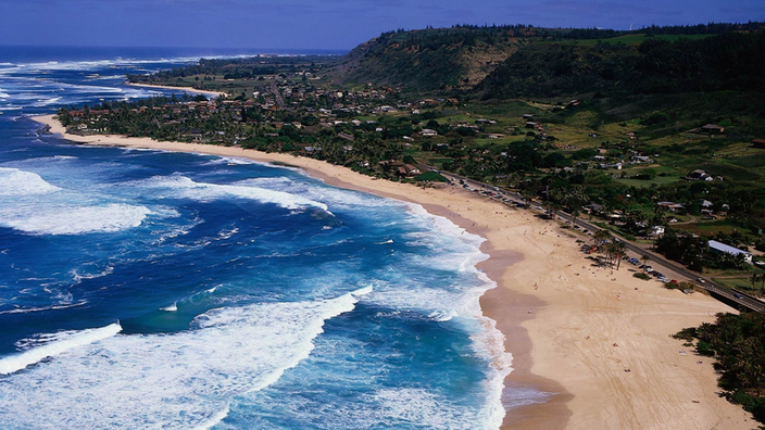 Luftaufnahme der Nordküste von Oahu mit Strand und vielen Wellen.