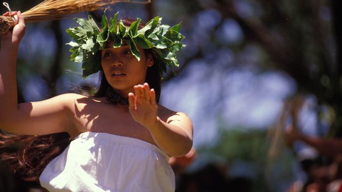 Auf Molokai tanzt eine Hawaiianerin in traditionellem Gewand und mit einem Blätterkranz auf dem Kopf den Hula. | Bildquelle: Mauritius Images/Photo Resource Auf Molokai tanzt eine Hawaiianerin in traditionellem Gewand und mit einem Blätterkranz auf dem Kopf den Hula.