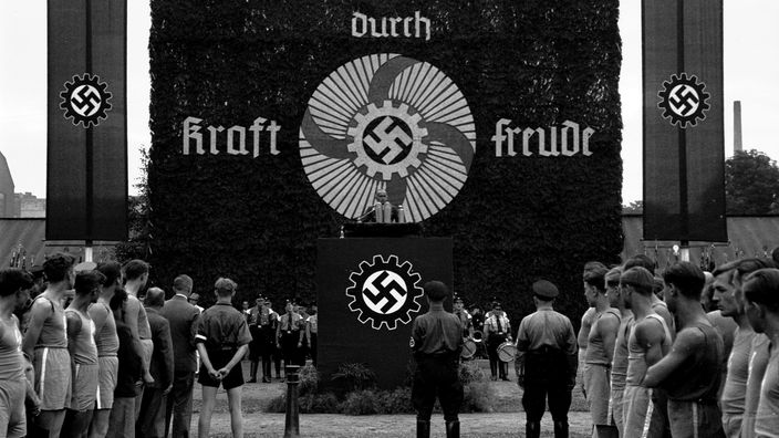 "Kraft durch Freude"-Banner und Rednerpult an einem Sportplatz 1937