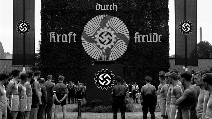 "Kraft durch Freude"-Banner und Rednerpult an einem Sportplatz 1937 | Bildquelle: akg "Kraft durch Freude"-Banner und Rednerpult an einem Sportplatz 1937