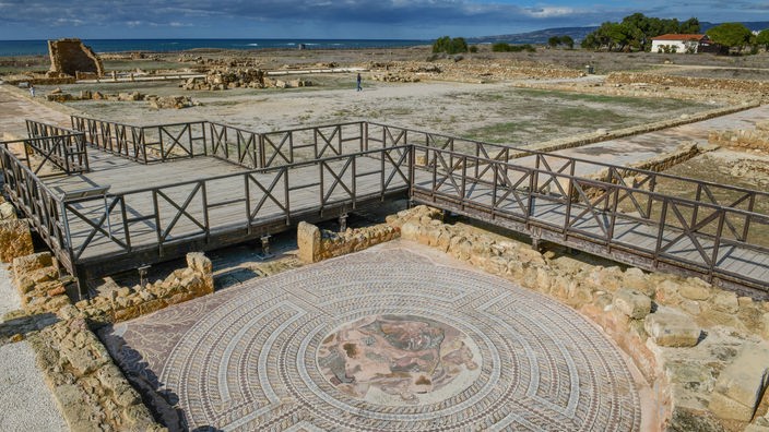 Eine Ausgrabungsstätte mit einem runden Mosaik auf dem Boden