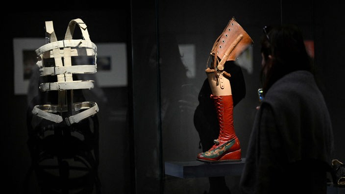 Der Besucher eines Museums schaut sich das Stahlkorsett und die Beinprothese Frida Kahlos an, die in einer Vitrine ausgestellt sind
