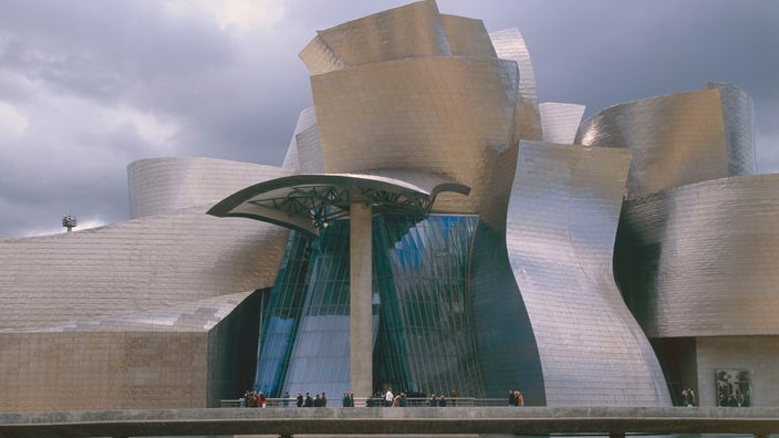 Das Guggenheim Museum in Bilbao: Ein futuristischer Bau aus Glas und Titan vor bedrohlich dunklem Himmel
